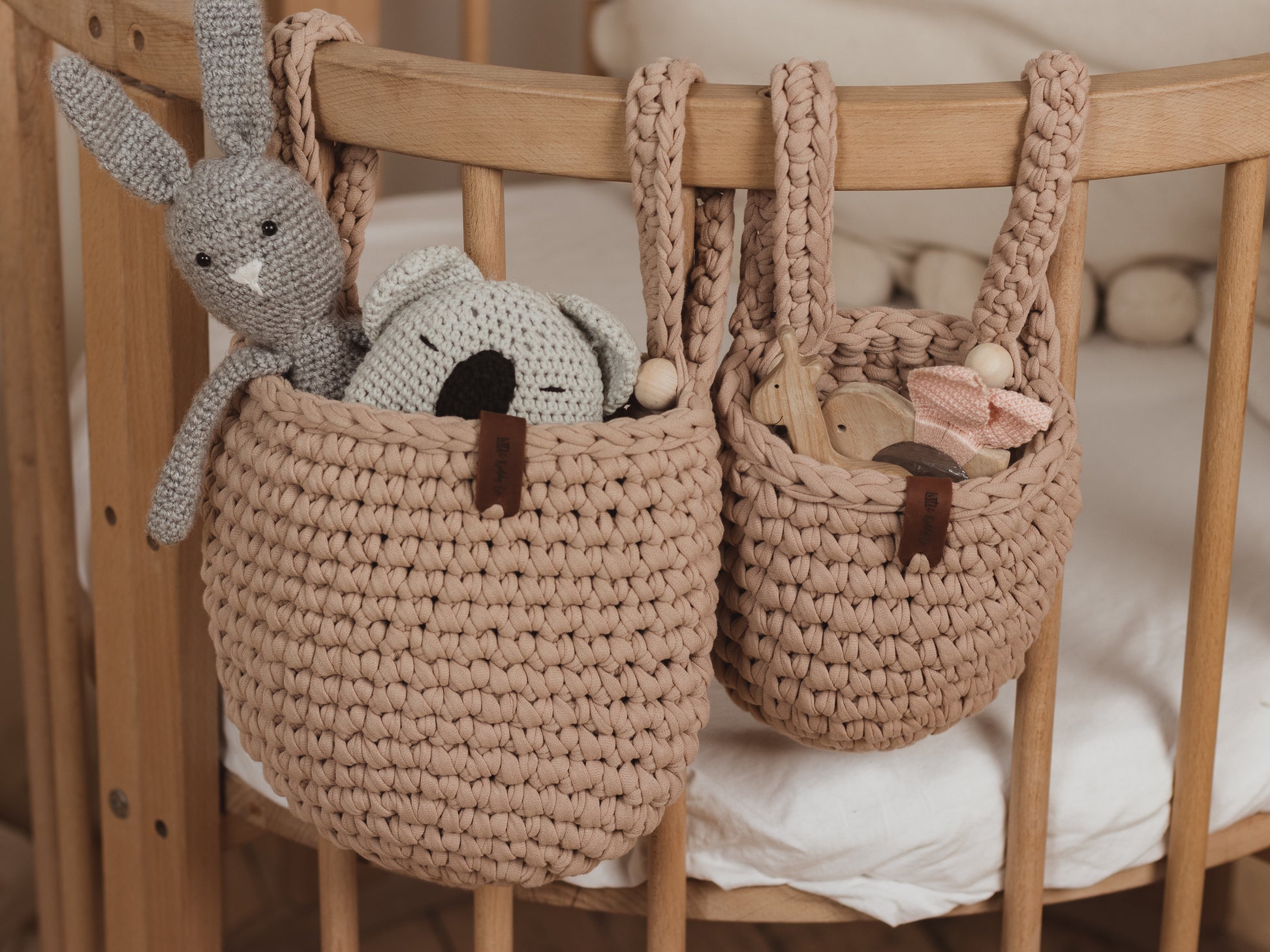 Two woven baskets with toys inside on a wooden crib.