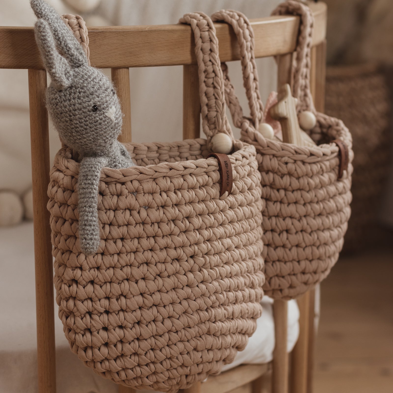 Two woven baskets with a knitted rabbit toy on a wooden chair.