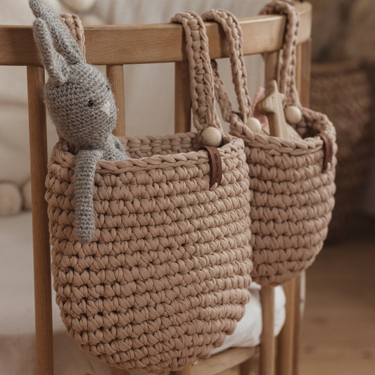 Two woven baskets with a knitted rabbit toy on a wooden chair.