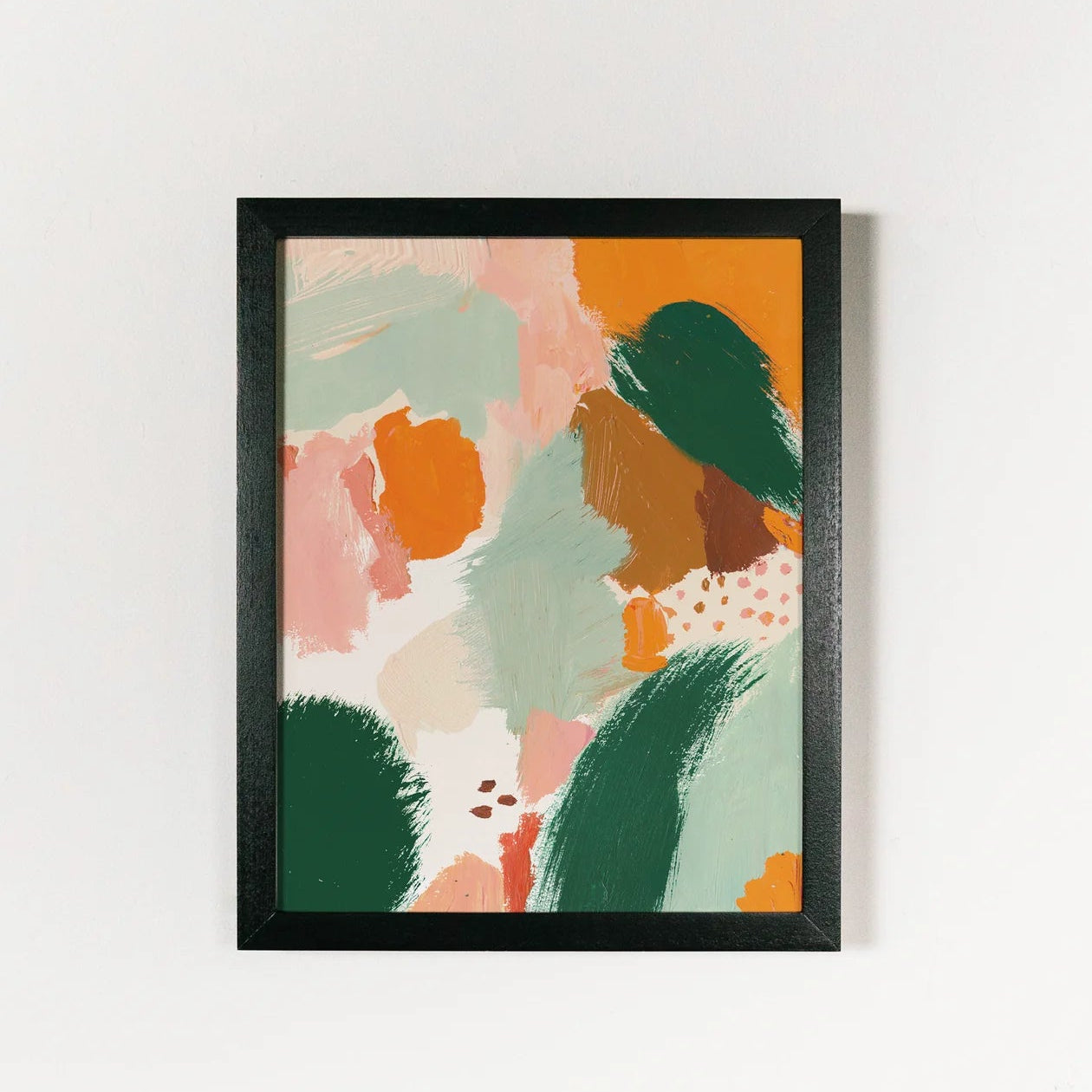 Framed abstract art print with colorful shapes on a white wall